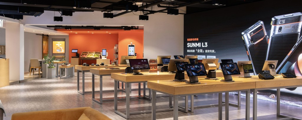 Sunmi technology showroom with wood display tables, POS hardware, grocery simulation area, and SUNMI L3 wall graphic